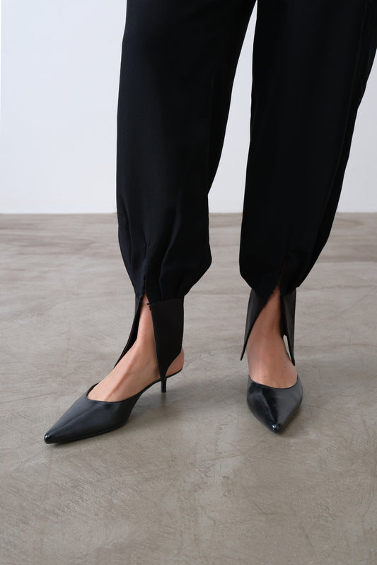 Close up of satin ankle cuff and pleat detail on black viscose blend trousers