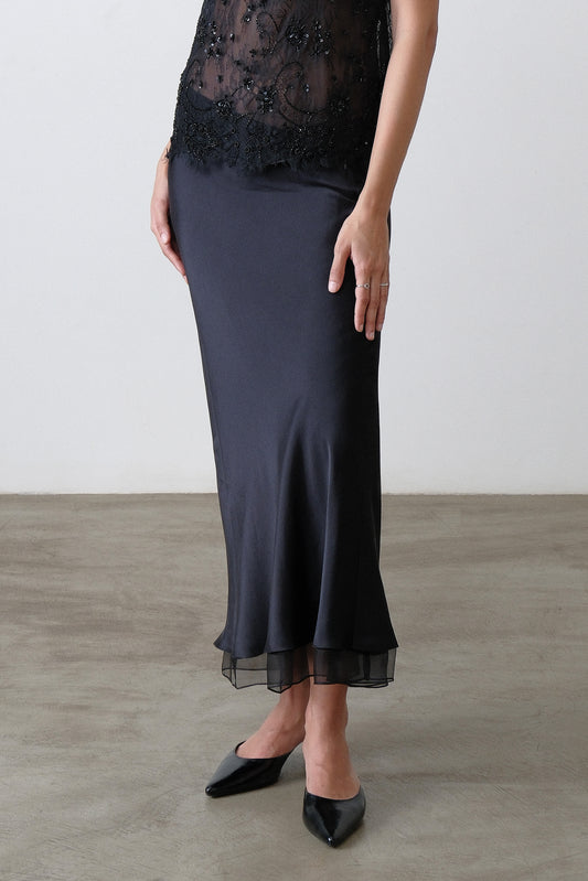 Close up of silk organza hem detail on black silk satin skirt