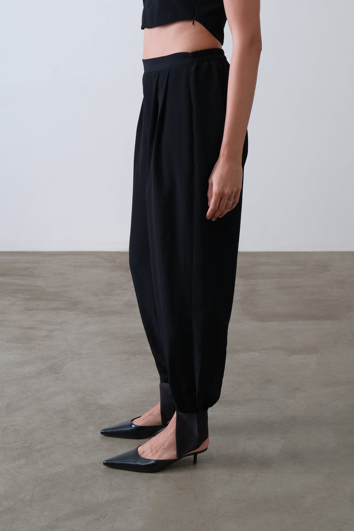 Side view of black viscose blend trousers with satin cuff and tapered leg