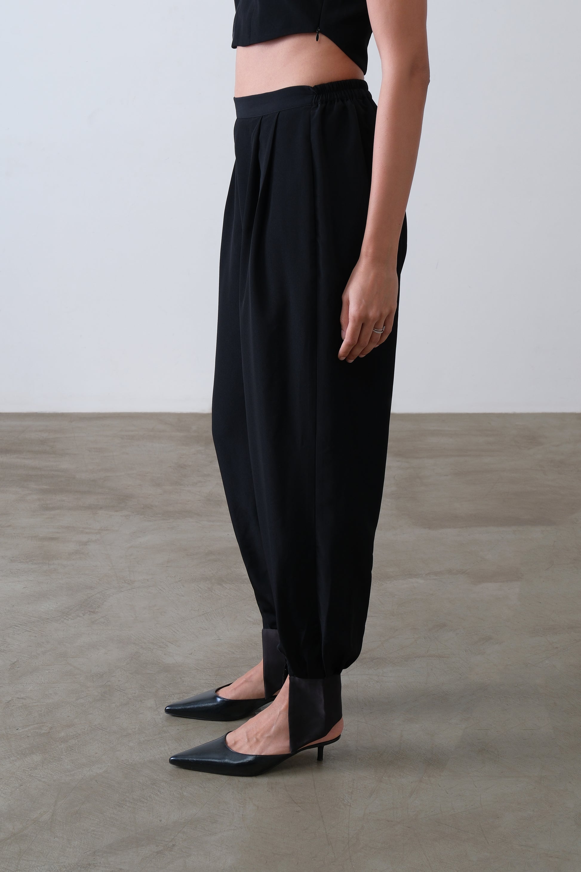 Side view of black viscose blend trousers with satin cuff and tapered leg