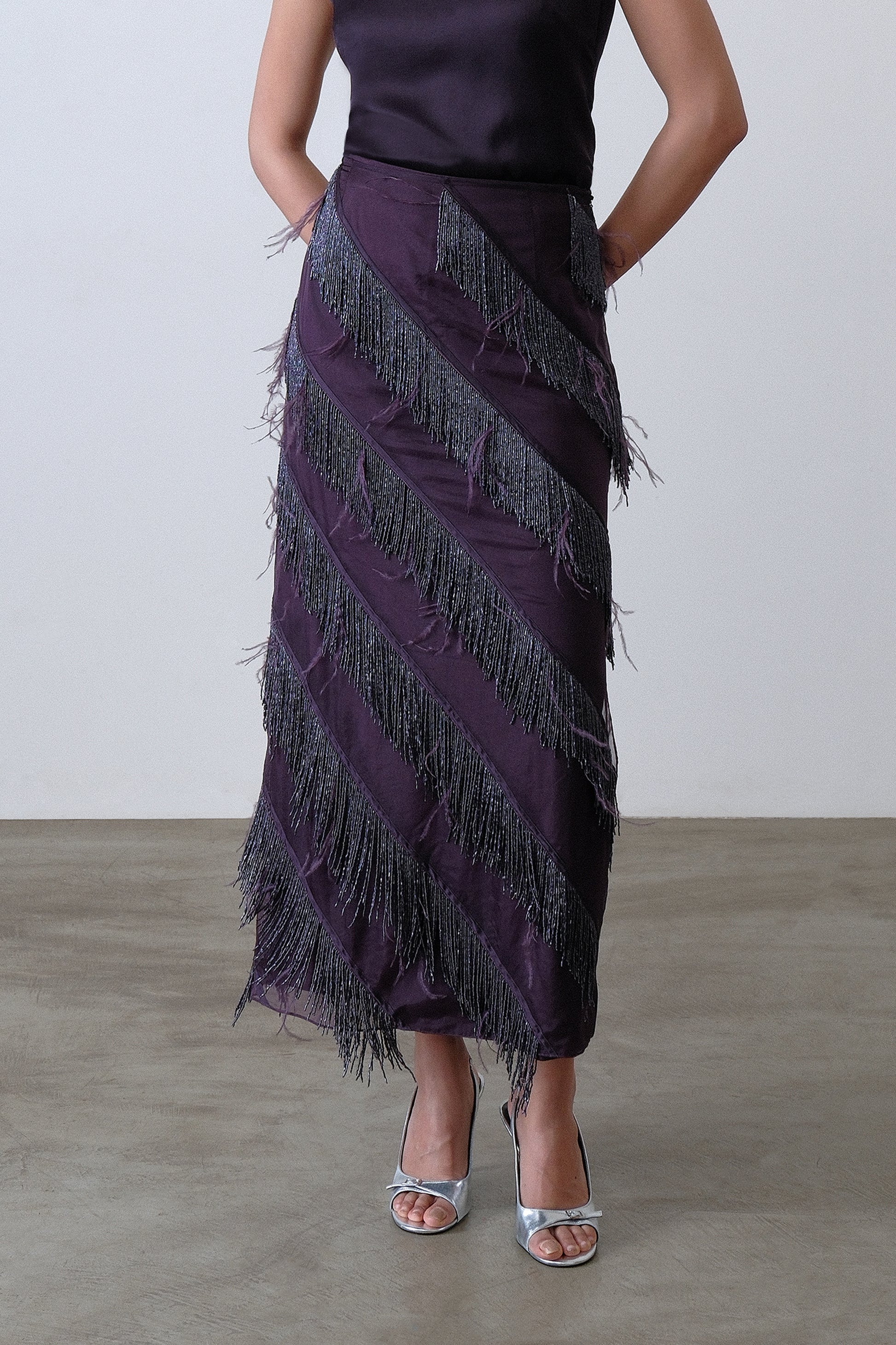 Close up of hand embroidered beaded fringe and feather detail on deep plum skirt