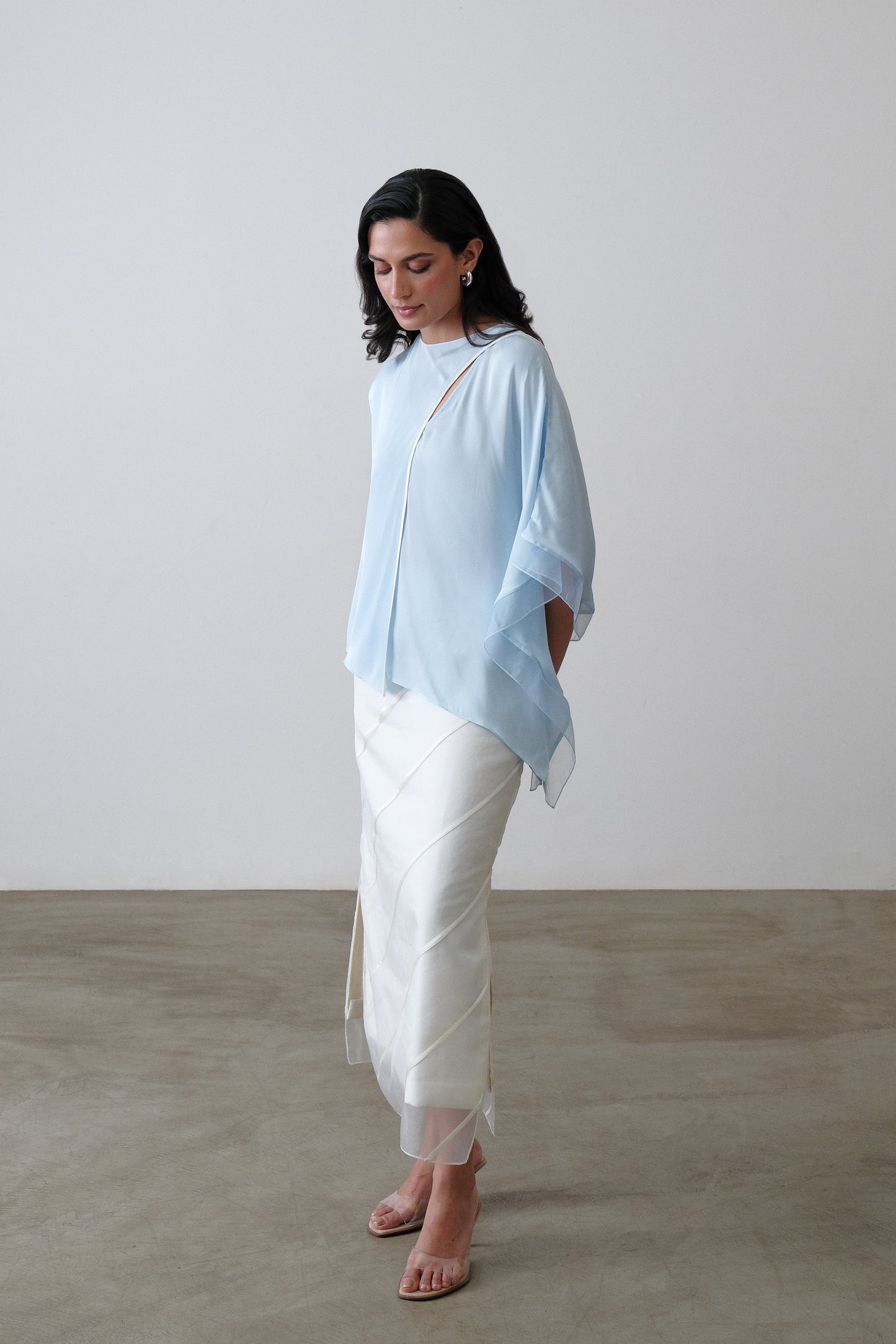 Powder blue silk satin georgette top shown at a three quarter angle with white piping and organza
